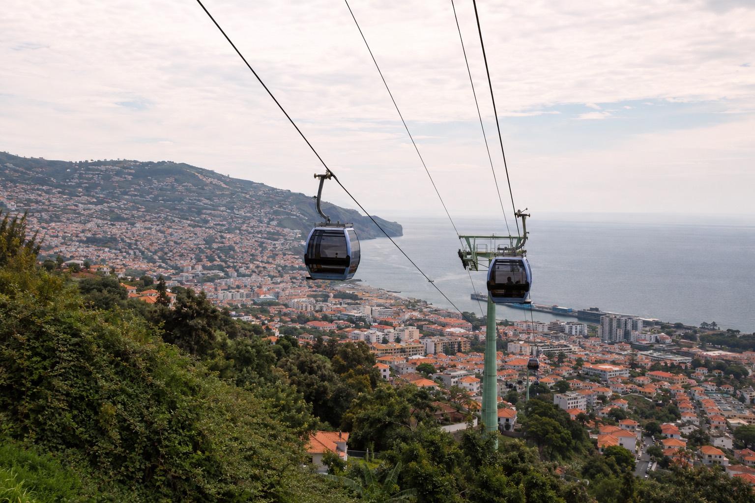 Cable car gondolas heading up toward Monte, with Funchal and the ocean below